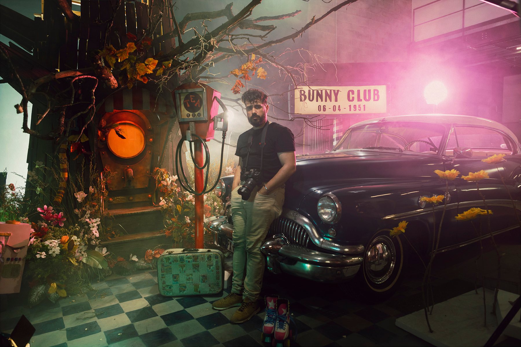 Un photographe, appareil en bandoulière, appuyé contre une voiture ancienne dans le décor du Bunny Club.